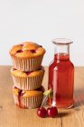 Свежеиспеченные вишневые кексы и бутылка фруктового напитка — стоковое фото