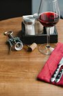 Um copo de vinho tinto, um saca-rolhas, talheres e saleiros de sal e pimenta em uma mesa — Fotografia de Stock