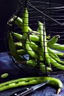 Green beans in nostalgic wire basket against black background — Stock Photo