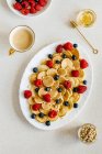 Mini pancakes arranged with berries, pine nuts and agave syrup — Stock Photo