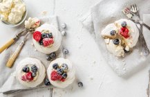 Meringue nests with raspberries and blueberries and whipped cream — Stock Photo