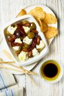 Feta with pickled olives, dried tomatoes, potato chips and olive oil — Stock Photo