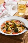 Minestrone in an enamel plate on a rustic wooden table — Stock Photo