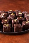 Hausgemachte Trüffel und Pralinen aus dunkler Schokolade mit essbarem Gold verziert — Stockfoto