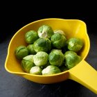 Brussels sprouts in yellow colander — Stock Photo