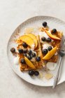 Belgian waffles with yoghurt, honey, blueberries and peach wedges — Stock Photo