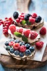 Berries and cream cheese bruschettas on wooden board — Stock Photo