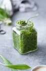 Green pesto sauce in glass jar on table — Stock Photo