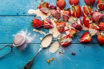 Morangos e natas cobertos com açúcar de confeiteiro e pétalas comestíveis — Fotografia de Stock