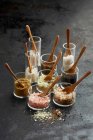 Натюрморт різних сортів солі в скляних банках з дерев'яними ложками — стокове фото
