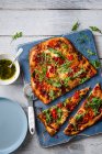 Pizza fatta in casa con salame, mozzarella, peperoni dolci, rucola e olio di basilico all'aglio — Foto stock
