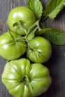 Tomates verdes e vermelhos em um fundo de madeira — Fotografia de Stock