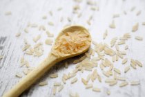 Long-grain rice on a wooden spoon on a wooden background — Stock Photo