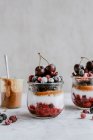 Sobremesas em frascos com framboesas, mirtilos, cerejas e manteiga de amendoim — Fotografia de Stock