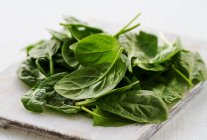 Foglie di spinaci freschi su un tagliere — Foto stock