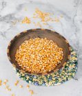Graines de maïs crues dans un bol sur fond blanc — Photo de stock