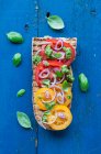 Offenes Sandwich, gegrilltes Baguette mit gelben und roten Tomaten, Basilikum-Pesto und roten Zwiebeln — Stockfoto
