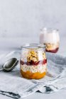 Cranberry and sea buckthorn sauce with granola in glass jar — Stock Photo