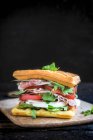 Un sándwich de gofres con jamón, tomate, mozzarella y cohete - foto de stock