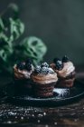 Magdalenas de chocolate con crema de café y moras espolvoreadas con azúcar en polvo - foto de stock