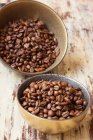 Grains de café dans un bol en bois sur un fond brun — Photo de stock