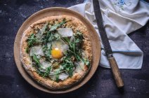 Pizza with fried egg, rocket and parmesan (top view) — Stock Photo