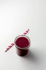 A berry smoothie in a glass with two drinking straws — Stock Photo
