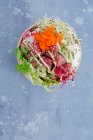 Poke bowl con atún, arroz de sushi, tobiko, rábanos, rodajas de pepino y brotes - foto de stock