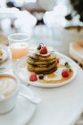 Matcha pancakes with raspberries blueberries and maple syrup — Stock Photo