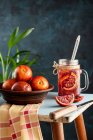 Скляна чашка лимонаду з кров'яним апельсином і свіжими фруктами в мисці — стокове фото