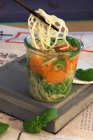 Asian noodle soup with peas, carrots and basil in a glass — Stock Photo