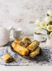 Filo rolls with Manouri cheese, walnuts, raisins, and mint; tea, white tulips — Stock Photo