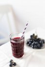 Red grape juice in glass with straw — Stock Photo