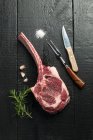 Raw tomahawk steak with rosemary and garlic — Stock Photo