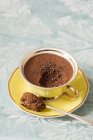 A yellow porcelain cup with mocha chocolate mousse on a light blue floral tablecloth — Stock Photo