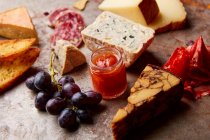 Assiette de hors-d'œuvre avec différents types de fromage, salami, raisins et pain — Photo de stock
