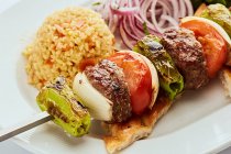 Minced beef skewer with onion, green pepper and tomato served with rice and flatbread — Stock Photo