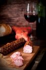 Salame de vinho tinto defumado feito de carne de porco e carne bovina em uma tábua de corte de madeira — Fotografia de Stock
