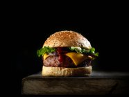 Hambúrguer saboroso fresco no fundo preto — Fotografia de Stock