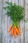 A bunch of baby carrots on a wooden surface (top view) — Stock Photo