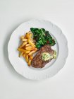 Стейк из говядины с травяным маслом, салатом и картошкой фри — стоковое фото