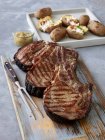 Gegrillte Rinderkoteletts, Zwiebelpüree und gegrillte Kartoffeln mit Speck und saurer Sahne — Stockfoto