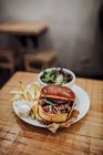 Plan rapproché de délicieux burger de bœuf haché servi avec salade et frites — Photo de stock