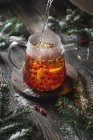 Brewing black tea with viburnum berries and lemon with fir branches and snow — Stock Photo