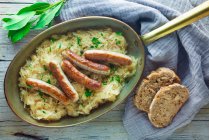 Sausages on sauerkraut in a copper pan — Stock Photo