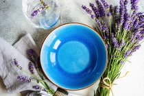 Mesa de verão com grés azuis e talheres decorados com flores frescas de lavanda — Fotografia de Stock
