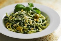 Spaghetti with spinach pesto and green olives — Stock Photo