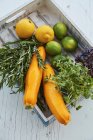 Rosemary, limões, limas, abobrinha e duas variedades de agrião em uma caixa de madeira — Fotografia de Stock