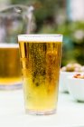 Pinte de bière avec cruche de bière derrière sur la table extérieure — Photo de stock