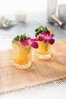 Два коктейля Май Тай, украшенные орхидеями и мятой в хрустальных бокалах — стоковое фото